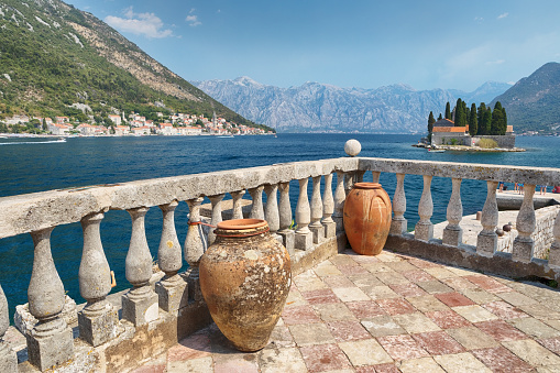 A view through a medieval architectural detail, on the left side townscape of Perast, on the right side St George Island with Saint George Benedictine monastery on it.