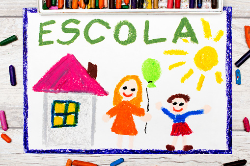 Photo of  colorful drawing: Portuguese word SCHOOL, school building and happy children. First day at school.