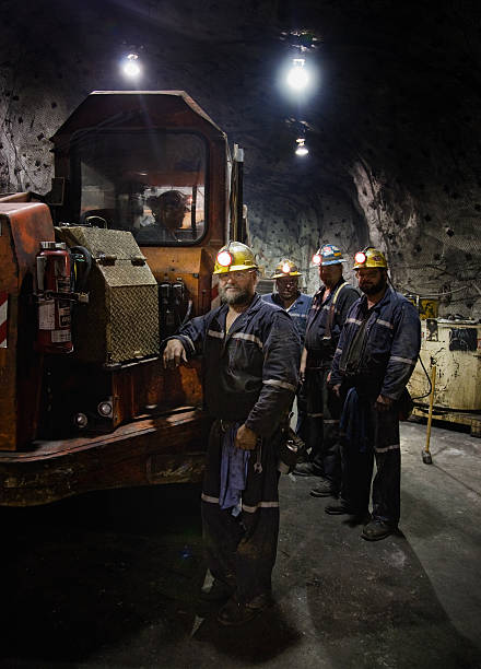 zinc miners with a 40-ton mine truck, portrait shot at 3100 feet below the surface in the truck maintenance room miner photos stock pictures, royalty-free photos & images