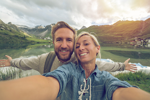 Young couple in Tignes, France taking a selfie portrait by the lake