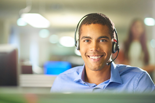 a young male call centre worker smiling to camera