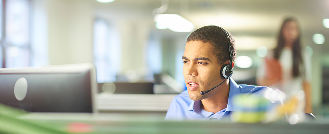 a young male call centre worker takes a call.