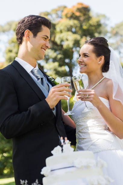 istock Newlywed toasting champagne flutes besides cake at park 843752924