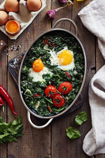 istock Eggs baked with spinach and tomatoes in serving pan overhead rustic wooden table. 843756384