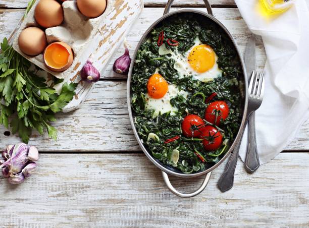istock Eggs baked with spinach and tomatoes in serving pan overhead rustic wooden table. 843759732