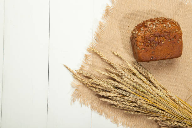 istock Rustic Bread and wheat on a white wooden background 843760294