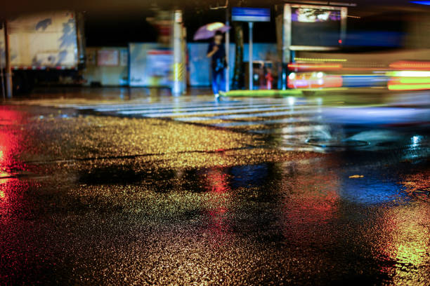 Rainy night in the big city Rainy night in the big city, light from the shop windows reflected on the road on which cars travel. View from the level of asphalt. kolkata night stock pictures, royalty-free photos & images