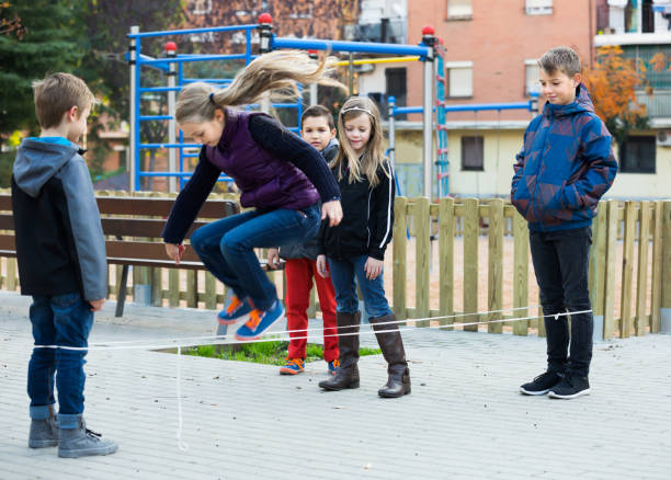 istock Friendly kids skipping on jumping elastic rope 843763024