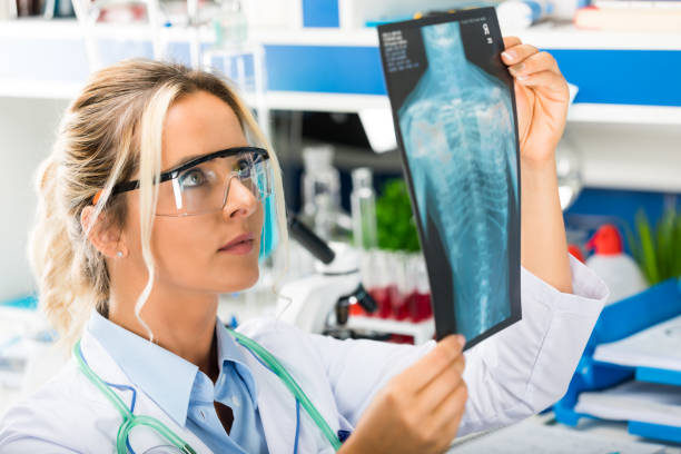 young attractive female scientist examining x-ray photography results - medical exam doctor patient adult imagens e fotografias de stock