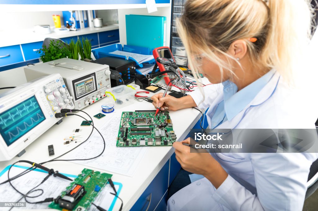 Female electronic engineer testing computer motherboard in laboratory Young female digital electronic engineer testing computer PC motherboard in laboratory Electronics Industry Stock Photo