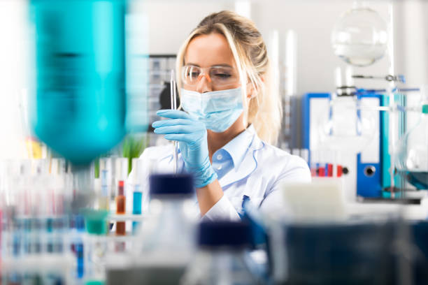 Young attractive female scientist preparing laboratory equipment for tests Young attractive female scientist in protective eyeglasses, gloves and mask preparing laboratory equipment for tests pharmaceutical factory photos stock pictures, royalty-free photos & images