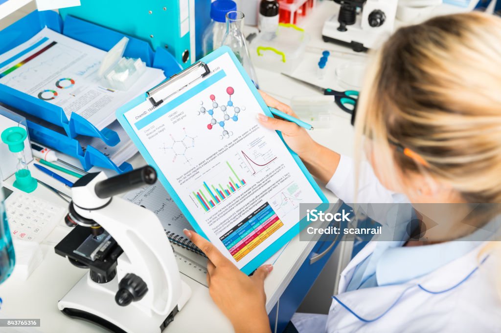 Young attractive woman scientist researching in the laboratory Young happy smiling attractive woman scientist in protective eyeglasses researching in the scientific chemical laboratory Science Stock Photo