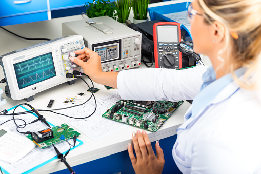 Young attractive female electronic engineer using digital oscilloscope in the laboratory