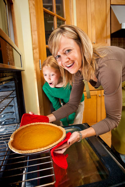семейная мать и дочь подготовка тыквенный пирог на день благодарения ужин - cooking thanksgiving women baking стоковые фото и изображения