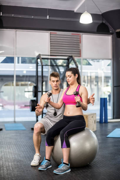 istock Male trainer assisting woman lifting dumbbells 843785242
