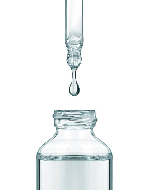 Drop falls from a pipette into a cosmetic bottle, isolated on white background