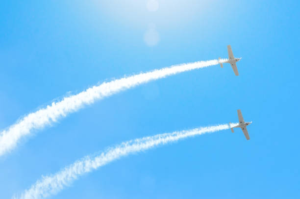 istock Light engine airplane with a trace of white smoke fly in groups in the blue sky with sunlight and glare 843786184