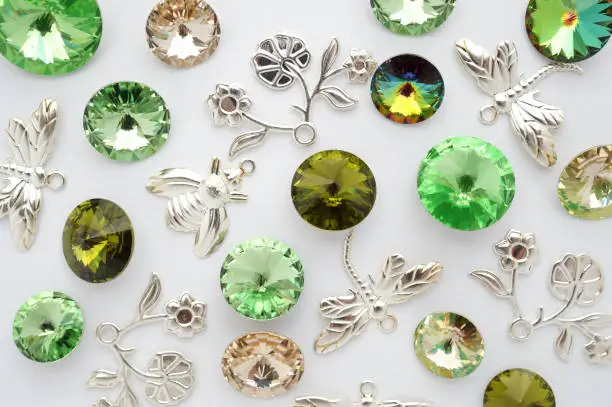 Photo of Green and gold crystals and metal bees and flowers and dragonflies on white background