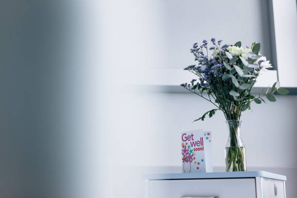 Get well soon card with flowers in hospital ward Get well soon card with flower vase on side table in hospital ward. get well soon stock pictures, royalty-free photos & images