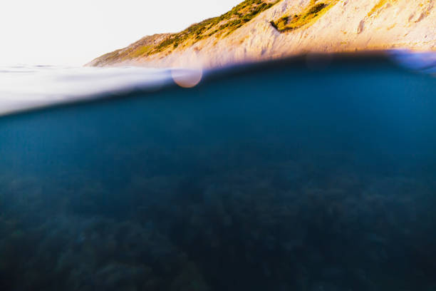 istock Underwater wave in ocean. Tropical sea with sunset light and rocks. 843803532