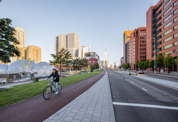 ROTTERDAM, NETHERLANDS - August 06, 2017: Cityscape view on the modern district with residential skyscrapers, floating pavillion and woman on the bicycle during the morning in Rotterdam