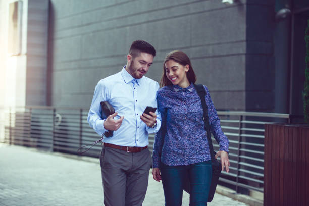 istock Two Smiling Colleagues with Smartphone Walking at Street After Work 843817314