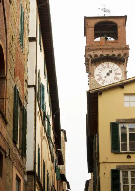 LUCCA, ITALY - AUGUST 15 2015: Tower clock in Lucca through buildings