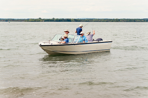 Five seniors brothers, from 65 to 80 year’s old, spending time together on a fishing trip. The boat just has left the beach, brothers are getting their fishing rod ready. Horizontal full length outdoors shot with copy space. This was taken in Quebec, Canada.