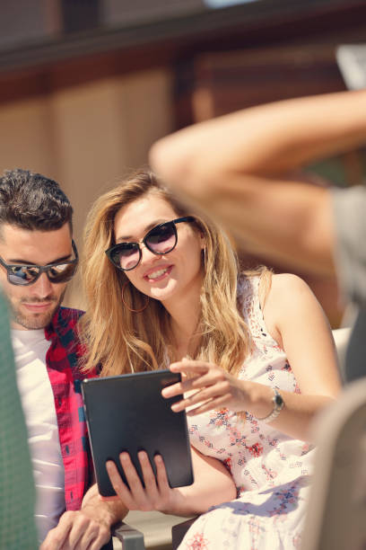 istock Beautiful stylish friends are using a digital tablet, drinking coffee and smiling while resting in the park 843867326