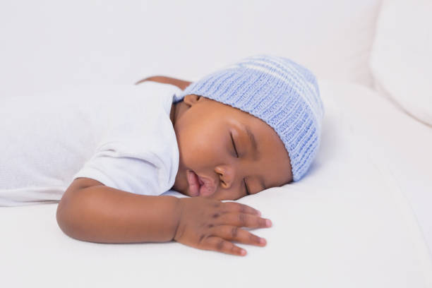 Adorable baby with head on hands wearing hand knit wool hat.