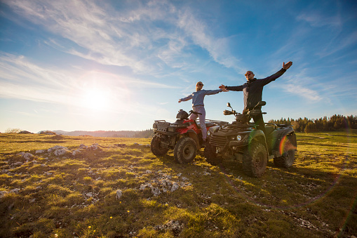 Couple driving off-road with quad bike or ATV.