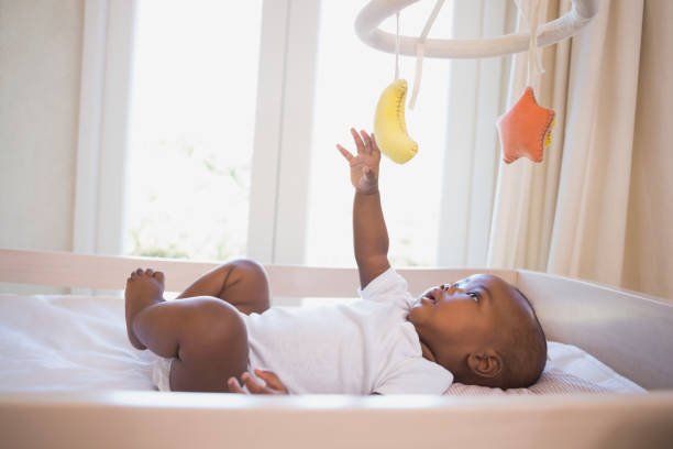 adorable bebé acostado en su cuna jugando con el móvil - cot fotografías e imágenes de stock