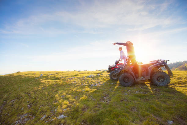 vista trasera del par joven cerca de atv. hombre está mostrando algo a distancia a su novia. - off road vehicle quadbike 4x4 stationary fotografías e imágenes de stock