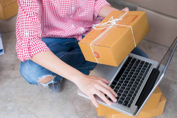istock start up small business owner checking product order with computer at workplace. freelance woman entrepreneur SME seller prepare parcel box for deliver to customer.  Online selling, internet marketing, e-commerce, shipping concept 843877854