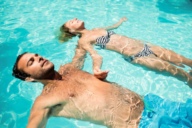 casal tranquilo flutuando na piscina - swimming trunks swimwear summer bikini - fotografias e filmes do acervo
