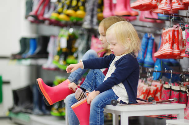 istock Two sisters choosing and trying on new rain boots 843888062