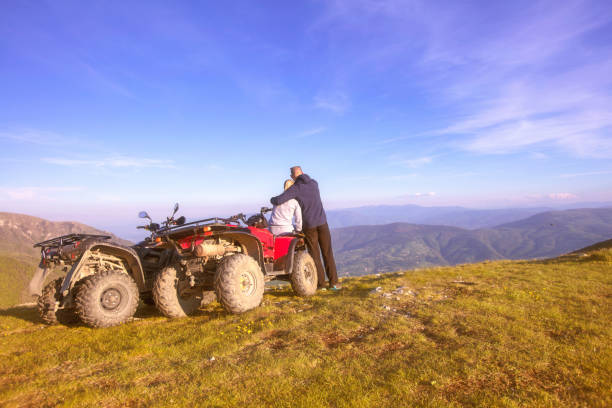 vista trasera del par joven cerca de atv. hombre está mostrando algo a distancia a su novia. - off road vehicle quadbike 4x4 stationary fotografías e imágenes de stock