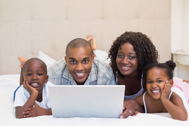 istock Happy family using laptop together on bed 843889006