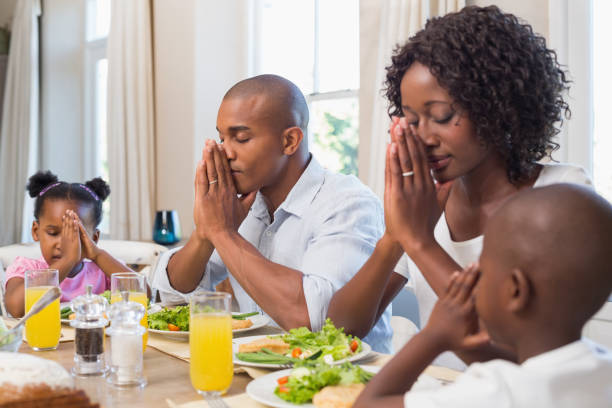 食事の前に恵みを言って幸せな家族 - praying saying grace dinner meal ストックフォトと画像