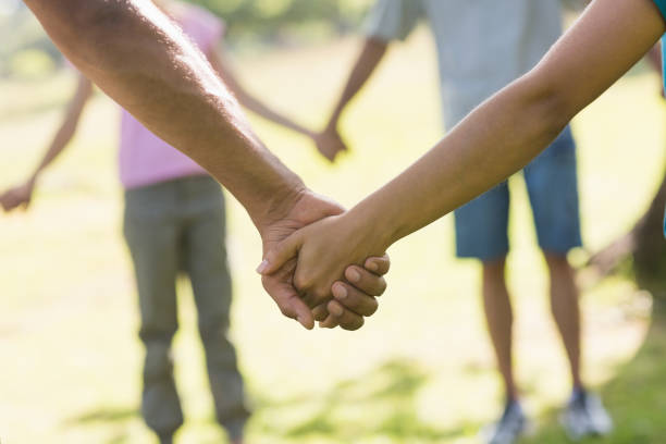istock Mid section of friends holding hands in park 843892374