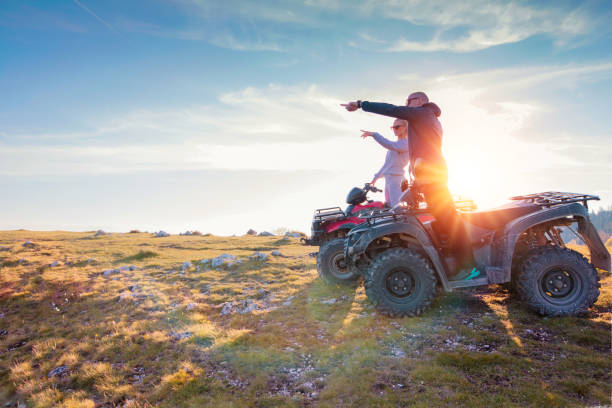 vista trasera del par joven cerca de atv. hombre está mostrando algo a distancia a su novia. - off road vehicle quadbike 4x4 stationary fotografías e imágenes de stock