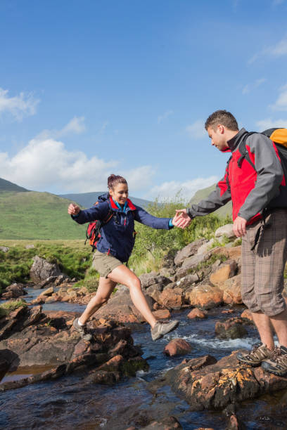 istock Man helping his girlfriend to cross a stream 843892784