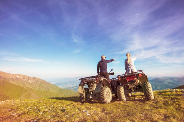 vista trasera del par joven cerca de atv. hombre está mostrando algo a distancia a su novia. - off road vehicle quadbike 4x4 stationary fotografías e imágenes de stock