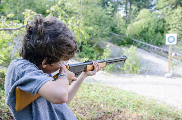 istock Little boy aiming at target with rifle during outdoors summer day vacations 843899062