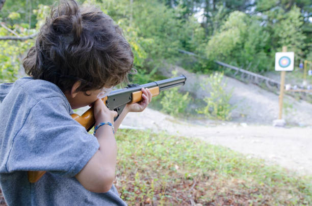 istock Little boy aiming at target with rifle during outdoors summer day vacations 843899118