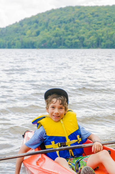 istock Young boy sit in kayak on a lake during outdoors summer day vacations 843899746