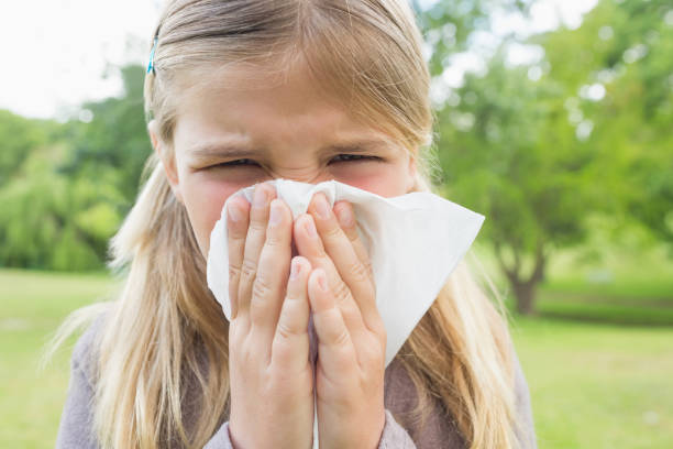 istock Girl blowing nose with tissue paper at park 843906048