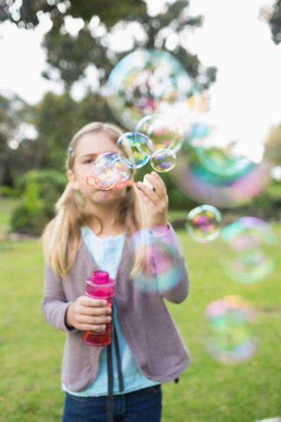 istock Girl blowing soap bubbles at park 843906102