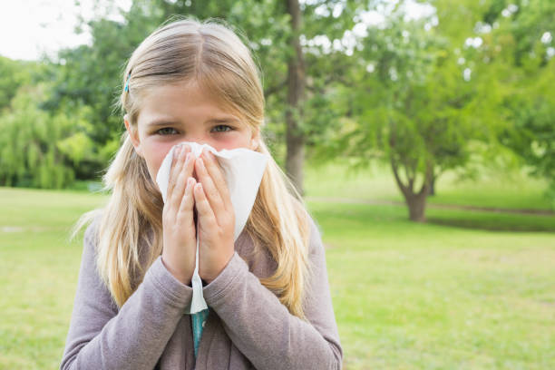 istock Girl blowing nose with tissue paper at park 843906136