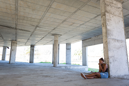 An African woman sits on her own and talks on her mobile phone